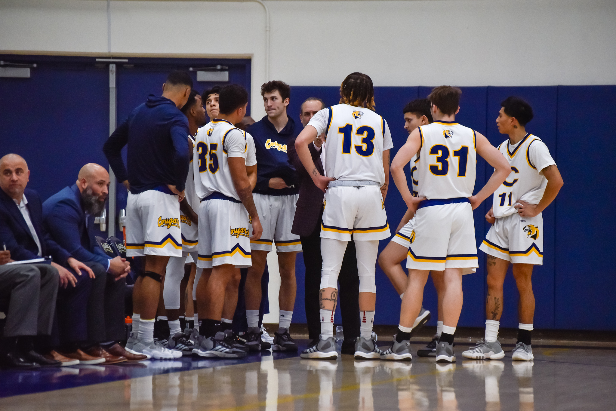 College of the Canyons men's basketball stock image of players huddled together on the sidelines.