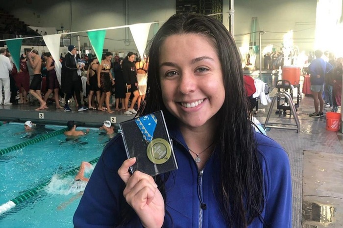 College of the Canyons swimmer Alyssa Hamilton standing in front of a pool and holding a swim medal during the 2023 Swim &amp; Dive State Championship meet on May 5, at East L.A. College.
