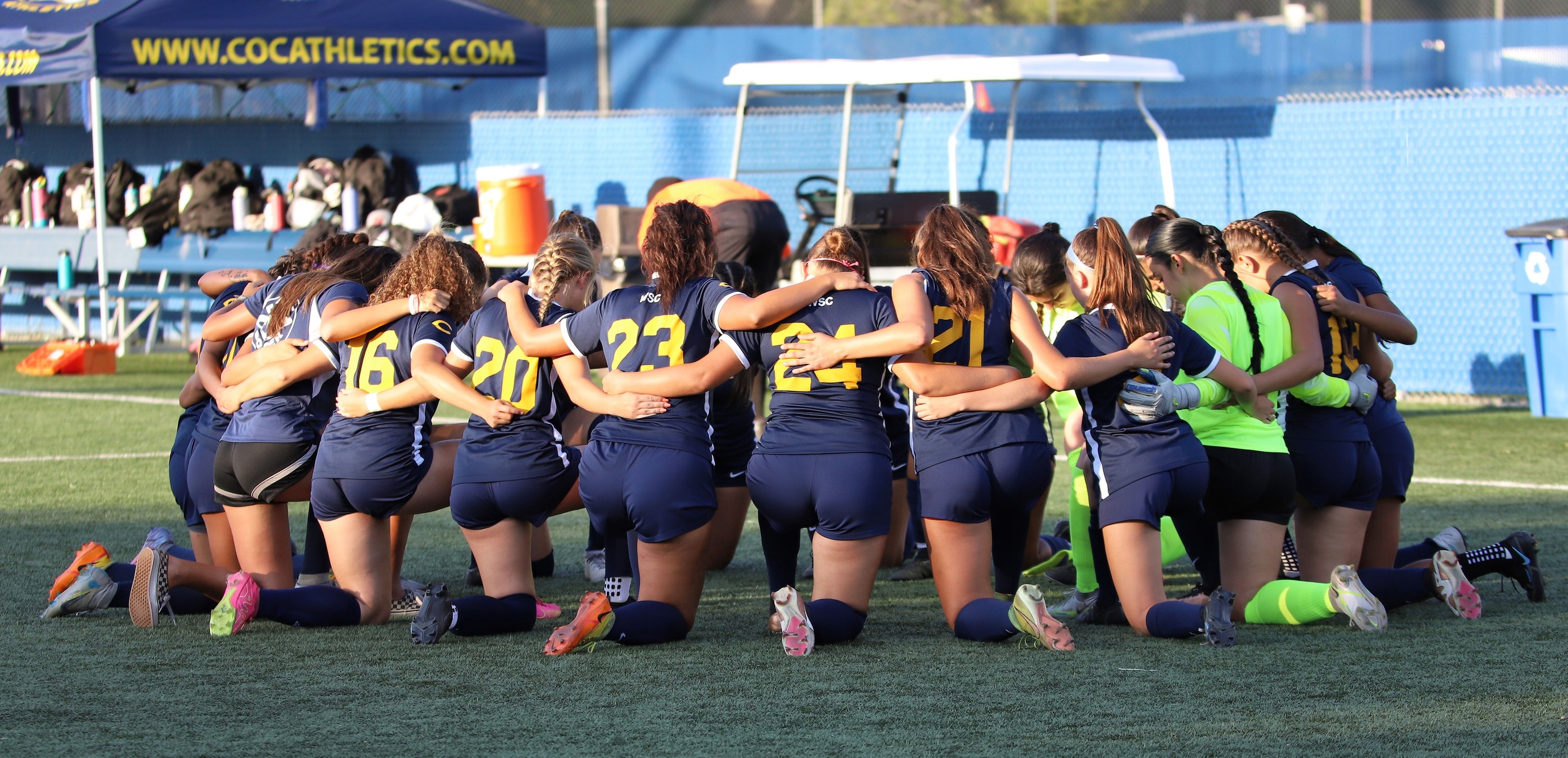 Stock image of the College of the Canyons women's soccer team kneeling in a huddle.