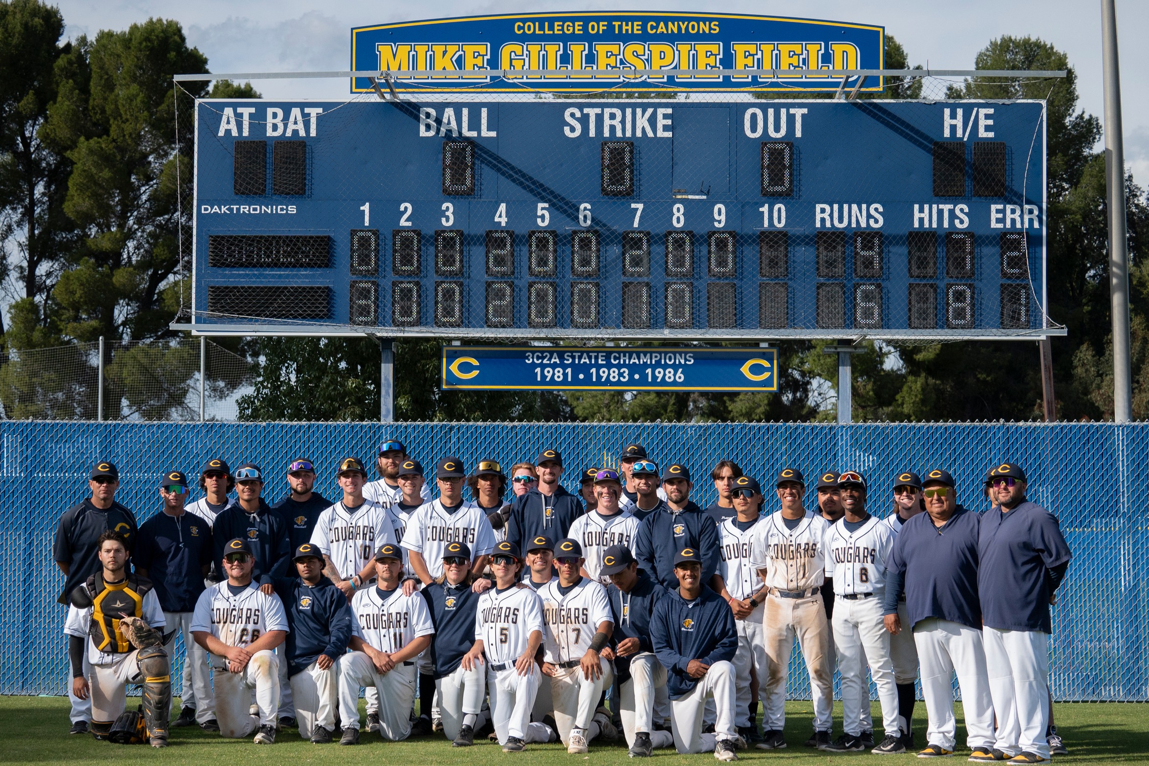Group picture of the College of the Canyons baseball team standing in front of the newly installed Mike Gillespie Field scoreboard.